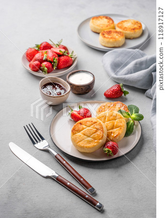 Cottage cheese, cheesecakes or syrniki with strawberries, sour cream, jam and mint leaves Cottage cheese, cheesecakes or syrniki with strawberries, sour cream, jam and mint leaves 118917127