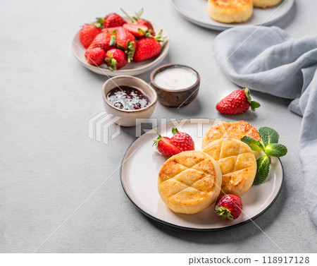 Cottage cheese, cheesecakes or syrniki with strawberries, sour cream, jam and mint leaves  118917128