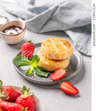 Cottage cheese, cheesecakes or syrniki with strawberries, berry jam and mint leaves  118917134