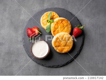 Cottage cheese, cheesecakes or syrniki with sour cream, strawberries and mint leaves Cottage cheese, cheesecakes or syrniki with sour cream, strawberries and mint leaves 118917142