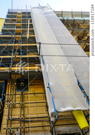 House restoration using metal tube scaffolding and plastic debris pipe covered with safety mesh House restoration using metal tube scaffolding and plastic debris pipe covered with safety mesh 118917184