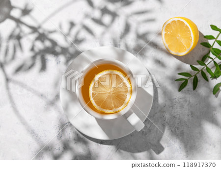 A cup of tea with lemon and green branch on a white table.  Breakfast detox and healthy concept. 118917370