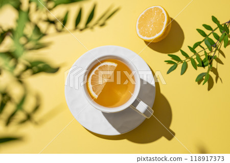 Herbal tea with lemon in a white cup on a yellow background. 118917373