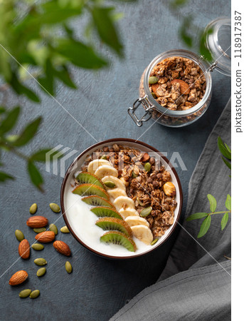 Granola or muesli with yogurt and banana on a dark background with branch. 118917387