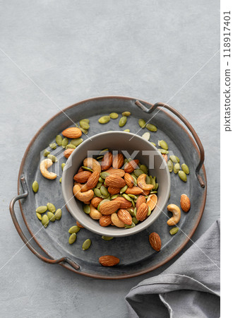 Mix of nuts. Almonds, cashews and pumpkin seeds in a bowl on a gray background with napkin. Mix of nuts. Almonds, cashews and pumpkin seeds in a bowl on a gray background with napkin. 118917401