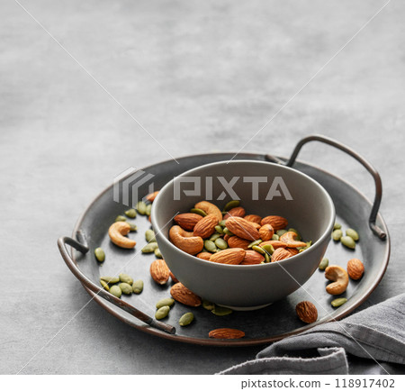 Mix of nuts. Almonds, cashews and pumpkin seeds in a bowl on a gray background with napkin. 118917402
