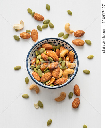 Mix of nuts. Almonds, cashews and pumpkin seeds in a bowl on a white wooden background. Mix of nuts. Almonds, cashews and pumpkin seeds in a bowl on a white wooden background. 118917407