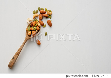 Mix of nuts. Almonds, cashews and pumpkin seeds in a wooden spoon are scattered Mix of nuts. Almonds, cashews and pumpkin seeds in a wooden spoon are scattered 118917408