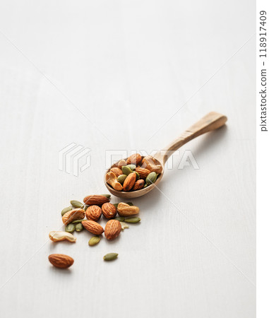 Mix of nuts. Almonds, cashews and pumpkin seeds in a wooden spoon are scattered Mix of nuts. Almonds, cashews and pumpkin seeds in a wooden spoon are scattered 118917409