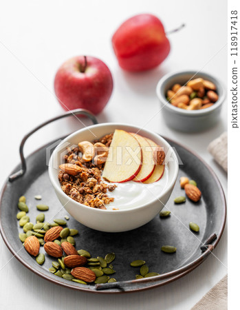 Healthy breakfast. Homemade granola or muesli with apple and nuts in a bowl on a white background. 118917418
