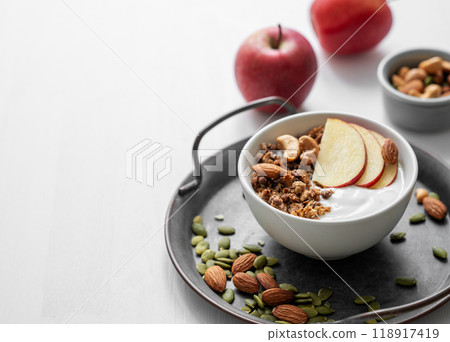 Healthy breakfast. Homemade granola or muesli with apple and nuts in a bowl on a white background. 118917419