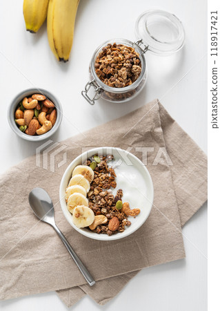 Granola or muesli with yogurt and banana on a white wooden table. 118917421