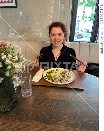 Millennial woman enjoying a delicious meal at a chic luxury restaurant, seated with a beautifully arranged plate of food. Stylish and inviting, creating a perfect dining experience Millennial woman enjoying a delicious meal at a chic luxury restaurant, seated with a beautifully arranged plate of food. Stylish and inviting, creating a perfect dining experience 118917548