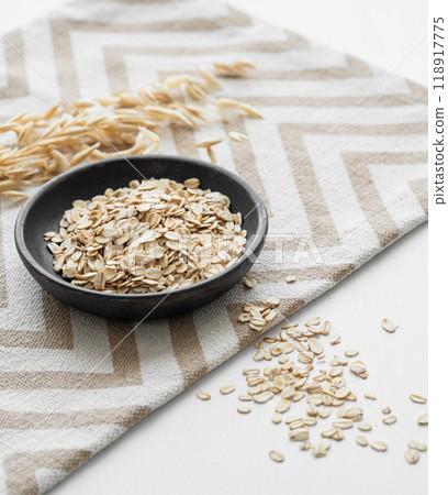 Oatmeal in a plate on a napkin on a white textured background with dry branch close up. 118917775