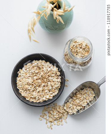 Oatmeal in a plate, jar and in a scoop on a white textured background. Oatmeal in a plate, jar and in a scoop on a white textured background. 118917785