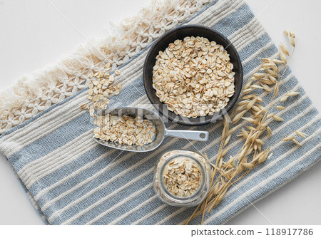 Oatmeal in a plate, jar and in a scoop on a napkin on a white textured background with dry branch. Oatmeal in a plate, jar and in a scoop on a napkin on a white textured background with dry branch. 118917786