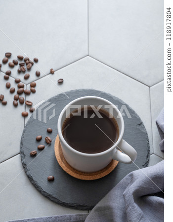 A cup of black coffee on a slate on a trendy gray tile background with coffee beans, napkin A cup of black coffee on a slate on a trendy gray tile background with coffee beans, napkin 118917804