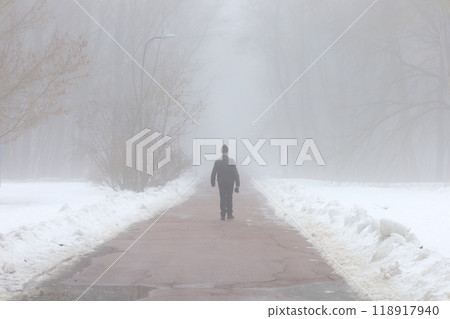 Silhouette of a man in thick fog, Winter park atmosphere, one man walking 118917940