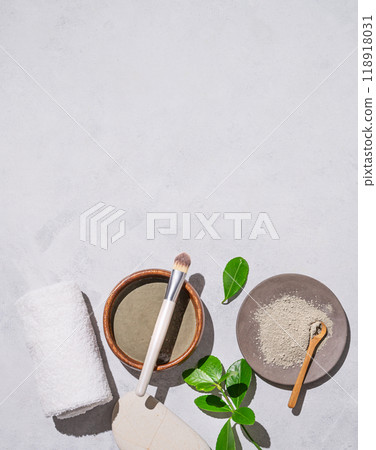 Homemade cosmetics. Organic clay in a bowl with a brush on a light background with shadow and leaves Homemade cosmetics. Organic clay in a bowl with a brush on a light background with shadow and leaves 118918031