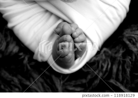 Foot of a newborn. Close up feet, toes, heels, feet of a newborn baby. Studio monochrome, vintage style, black and white macro photography. Foot of a newborn. Close up feet, toes, heels, feet of a newborn baby. Studio monochrome, vintage style, black and white macro photography. 118918129