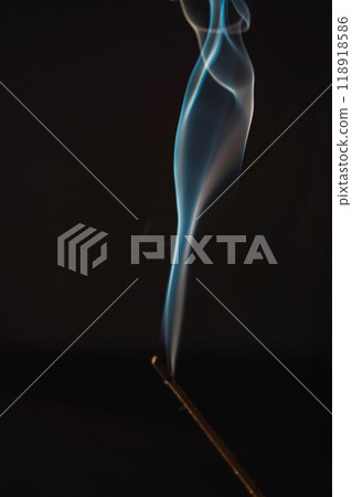 Incense burning smoke fumes and wisps. Aromatherapy smokes for yoga. Aroma sticks smoke on black background with white backlit. Burning aromatic incense smoky stick for meditation and relaxing. 118918586