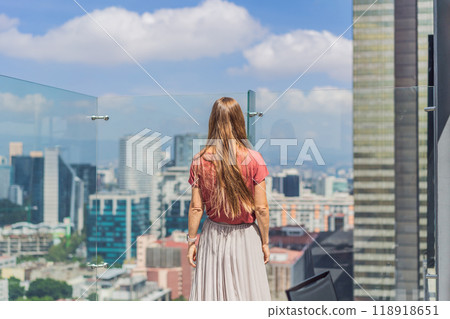 Female tourist or businesswoman standing on a skyscraper rooftop with a panoramic view of Mexico City. Travel or international business in Mexico concept 118918651