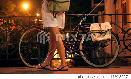 Woman stands with her classic bike on picturesque channel embankment in Annecy at night, France Woman stands with her classic bike on picturesque channel embankment in Annecy at night, France 118918937