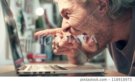 A bearded man laughs out loud when using his laptop 118918973