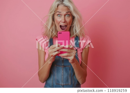 An older woman is holding a cell phone and laughing 118919259