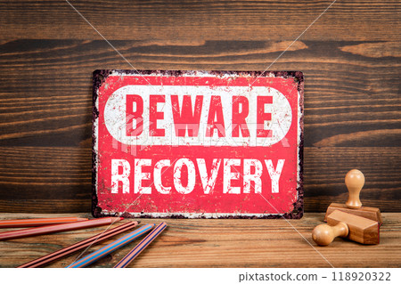 Recovery. Beware sign with text on a wooden texture office table 118920322