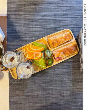 colorful breakfast spread showcases sliced fruits and pastries on a wooden tray, offering a vibrant start to the day. accompanied by glasses of water, this arrangement exudes freshness and simplicity. colorful breakfast spread showcases sliced fruits and pastries on a wooden tray, offering a vibrant start to the day. accompanied by glasses of water, this arrangement exudes freshness and simplicity. 118920341