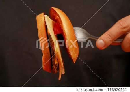 Hands holding homemade beef burger on wooden table. Ready to eat tasty fast food hamburger. Unhealthy food concept. Man holds burger with hands. Home delivery. Close up shot of young man eats burger. 118920711