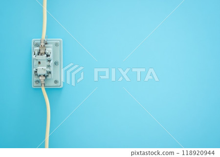 A close up view of a utility junction box with a yellow cable on a blue wall in a modern indoor setting A close up view of a utility junction box with a yellow cable on a blue wall in a modern indoor setting 118920944