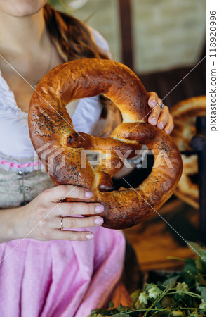 Traditional Bavarian pretzel held by a woman in traditional dress, perfect for Oktoberfest Traditional Bavarian pretzel held by a woman in traditional dress, perfect for Oktoberfest 118920996