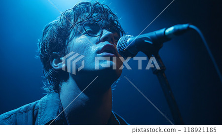 A man singing into a microphone with a microphone stand behind him 118921185