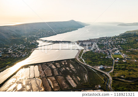 Aerial view of vast coastal salt pans with seawater pools and salt production. Aerial view of vast coastal salt pans with seawater pools and salt production. 118921321