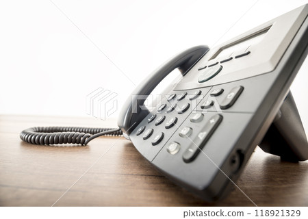 Black landline telephone instrument with a number pad on a rustic wooden desk Black landline telephone instrument with a number pad on a rustic wooden desk 118921329