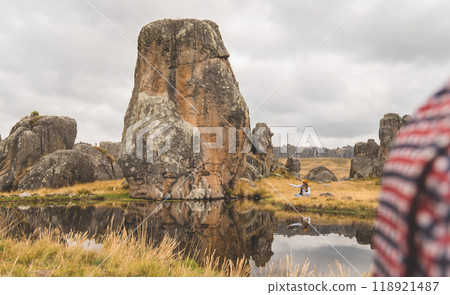 A woman sits in a field next to a river, tourist in the peruvian andes, Huayllay Stone Forest, Peru. 118921487