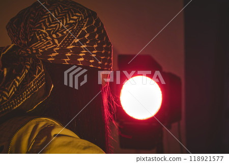A person wearing a scarf is standing in front of a red light. Urban dancer concept. 118921577