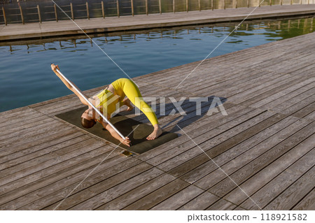 Engaging in a Yoga Practice by the Water on a Beautifully Sunny Day for Relaxation 118921582