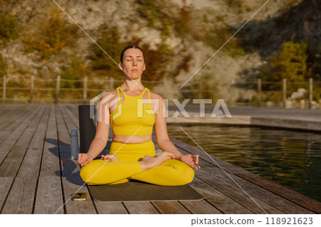 Enjoying a Peaceful Yoga Practice by the Lovely Lake While Dressed in Vibrant Yellow Attire 118921623
