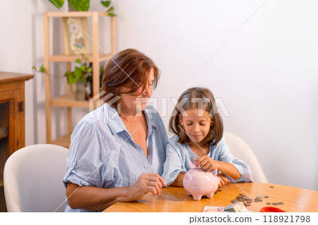 Cute girl inserting coin in piggy bank while Cute girl inserting coin in piggy bank while 118921798