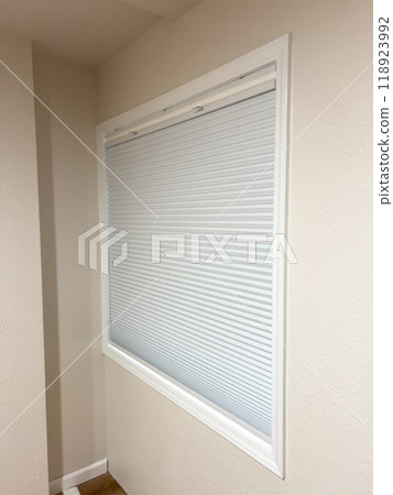White Window with Dual Cellular Blinds in Renovated Room. High quality photo A close-up of a window in a newly renovated room featuring modern dual cellular blinds. The blinds are partially open 118923992