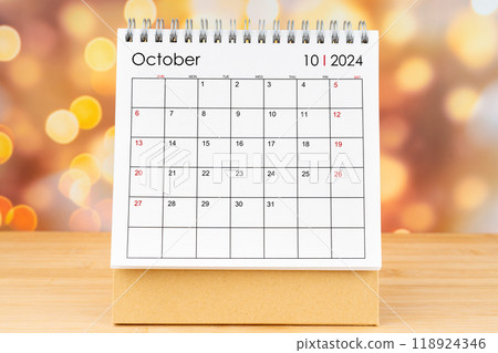 October 2024 desk calendar on wooden table with gold light bokeh background. 118924346