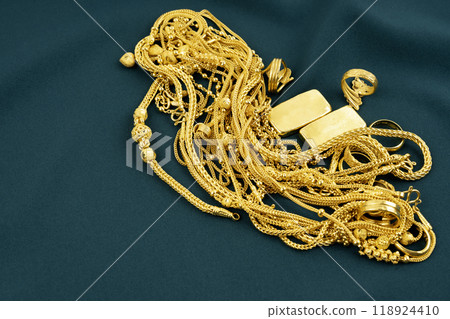 Many gold necklaces and gold bars on green velvet cloth 118924410