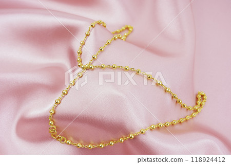 A Gold Necklace on pink color silk background. 118924412