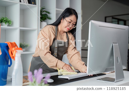 Housekeeper Skillfully Cleaning Office Desk and Accessories 118925185