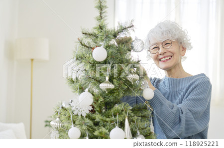 Senior woman decorating Christmas tree with ornaments Senior woman decorating Christmas tree with ornaments 118925221