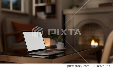A laptop with a white screen mockup on a coffee table in a cozy contemporary living room at night. A laptop with a white screen mockup on a coffee table in a cozy contemporary living room at night. 118925953