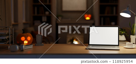 A laptop mockup on a table in a living room on Halloween night, illuminated by glowing lights. 118925954